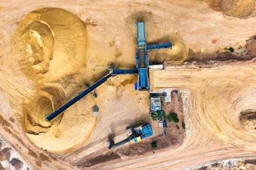 Drone shot of a sand quarry with conveyor belts and machinery in operation.